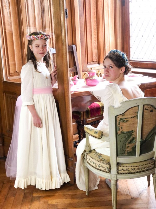 2 filles portant des robes de cérémonies blanche en plumetis de coton, robe de communion, cortège de mariage. Photo prise au chateau de Pontgibaud