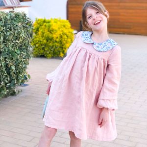 petite fille souriante portant une robe en lin rose à col claudine en liberty