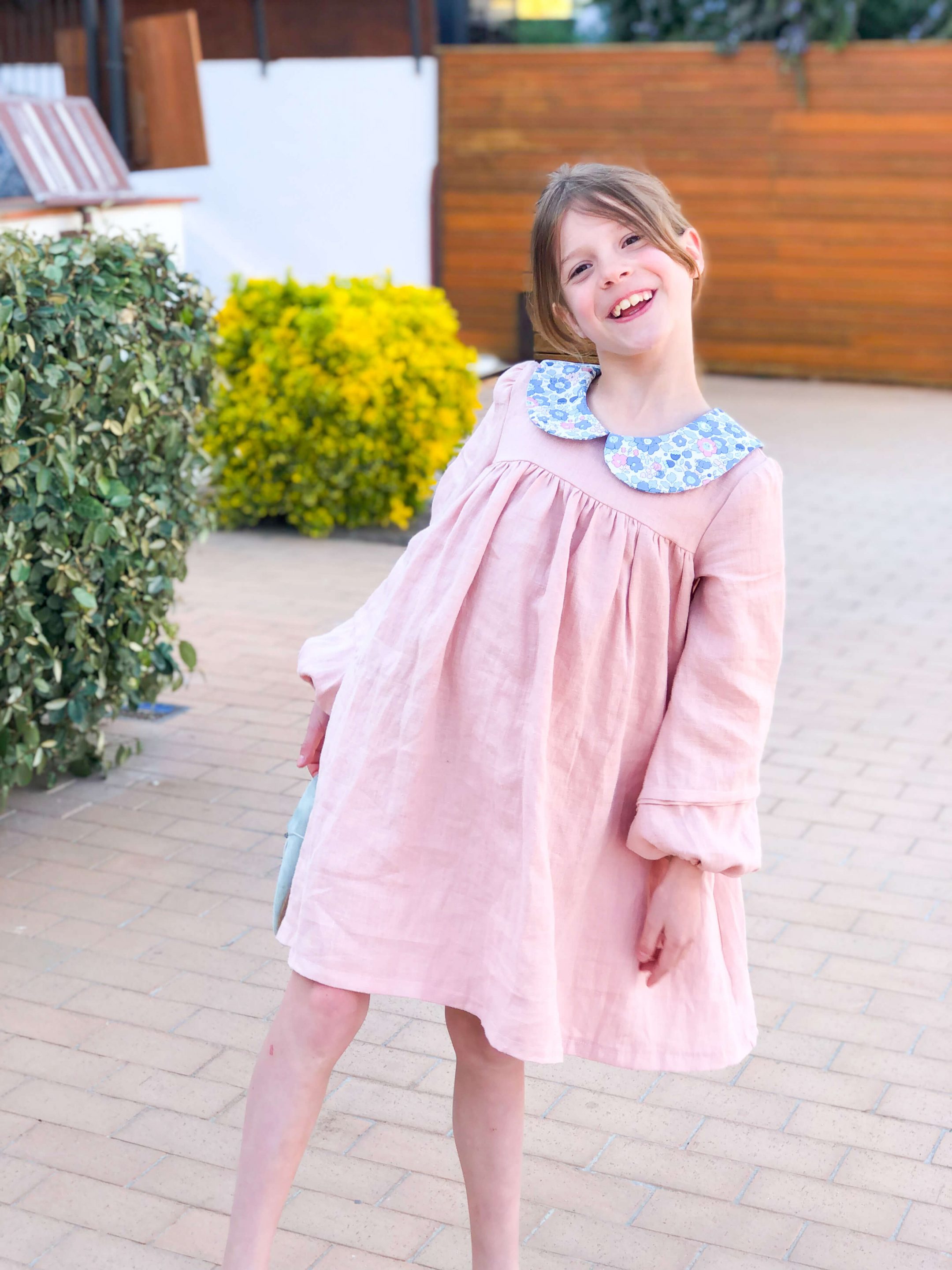 petite fille souriante portant une robe en lin rose à col claudine en liberty
