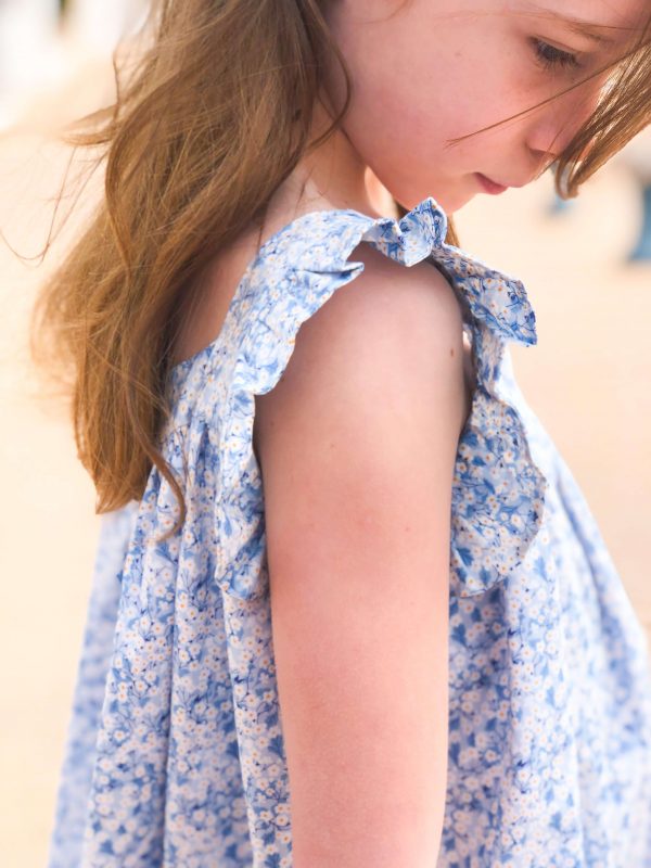 Petite fille romantique portant une robe en liberty bleue à manches volantées.