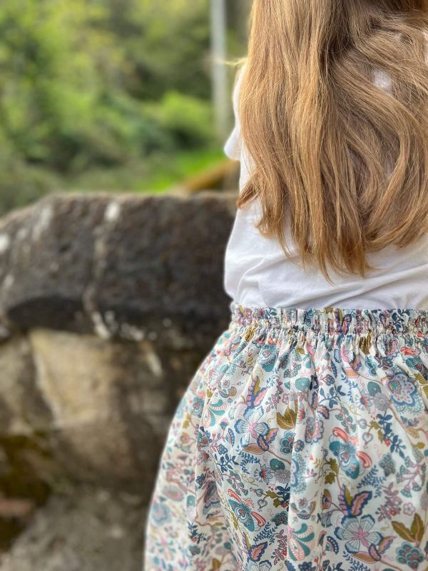 détail de la ceinture d'une jupe élastiquée liberty mabelle portée par une fillette aux cheveux blondes détachés.