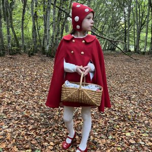 Le petit chaperon rouge se promène dans la forêt, elle porte un bonnet et une cape rouge en flanelle de laine et un panier
